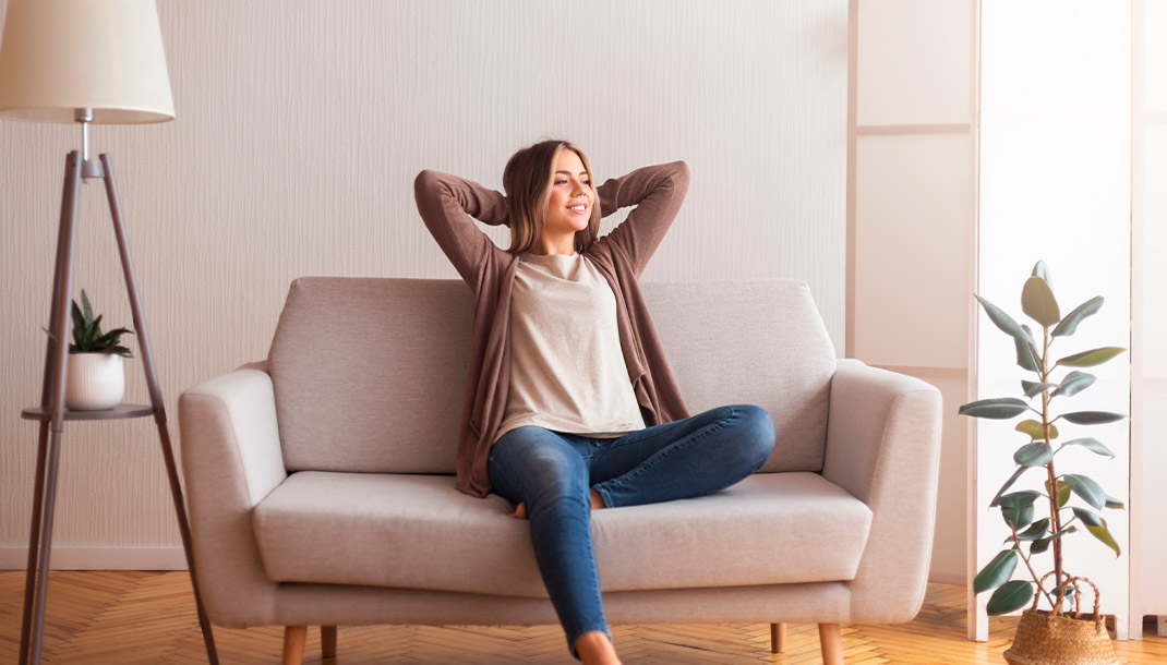 Mujer descansando en el sofá de su vivienda nueva con el proyecto de jóvenes propietarios