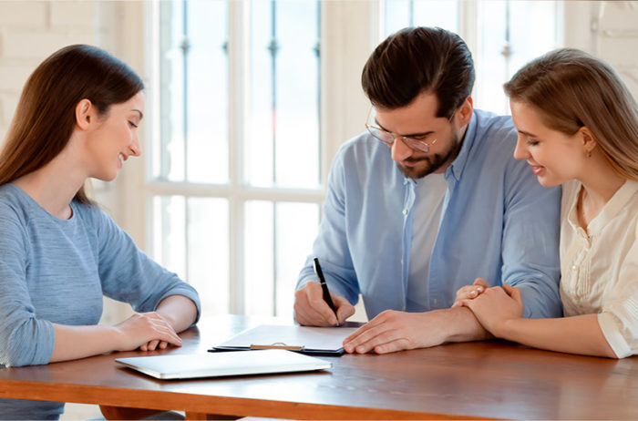 Pareja de adultos en la sala de ventas de cusezar firmando el contrato de compra de vivienda