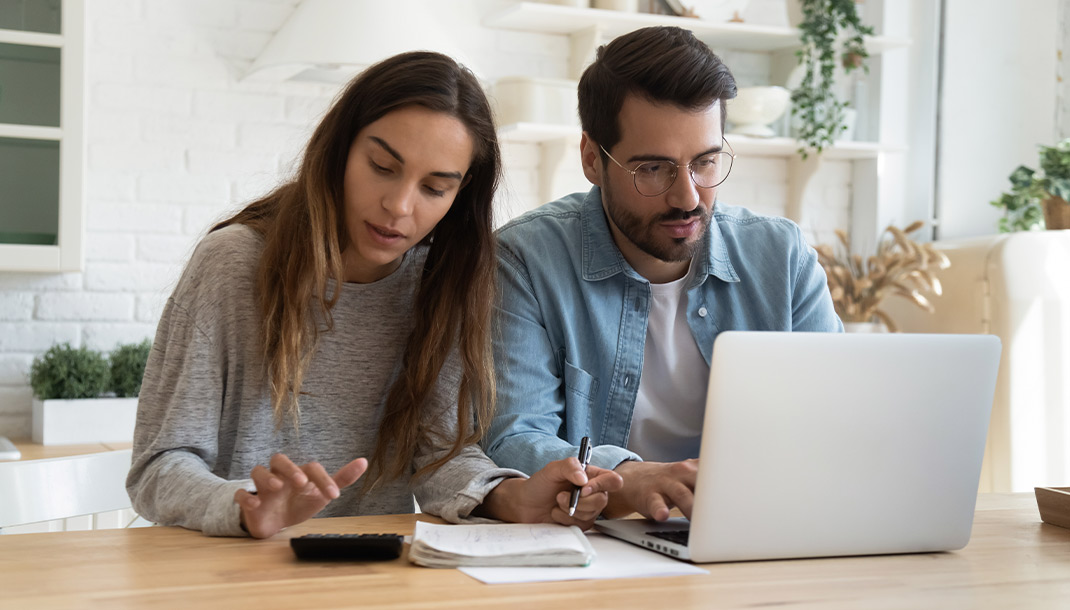 Pareja Joven en la sala de su casa revisando sus obligaciones financieras para comprar una vivienda.