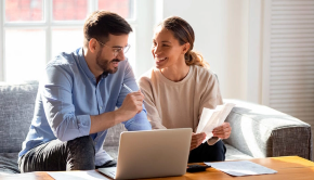 Pareja de adultos jóvenes en la sala de su casa organizandoze para comprar su primera vivienda